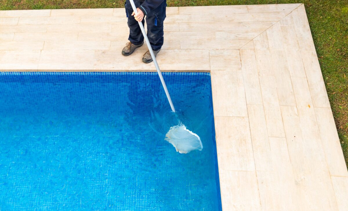 Pool cleaner sweeping the surface of the pool with a net.
